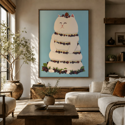 Whimsical cat cake canvas wall art displayed in a warm living room with olive tree and white sofa